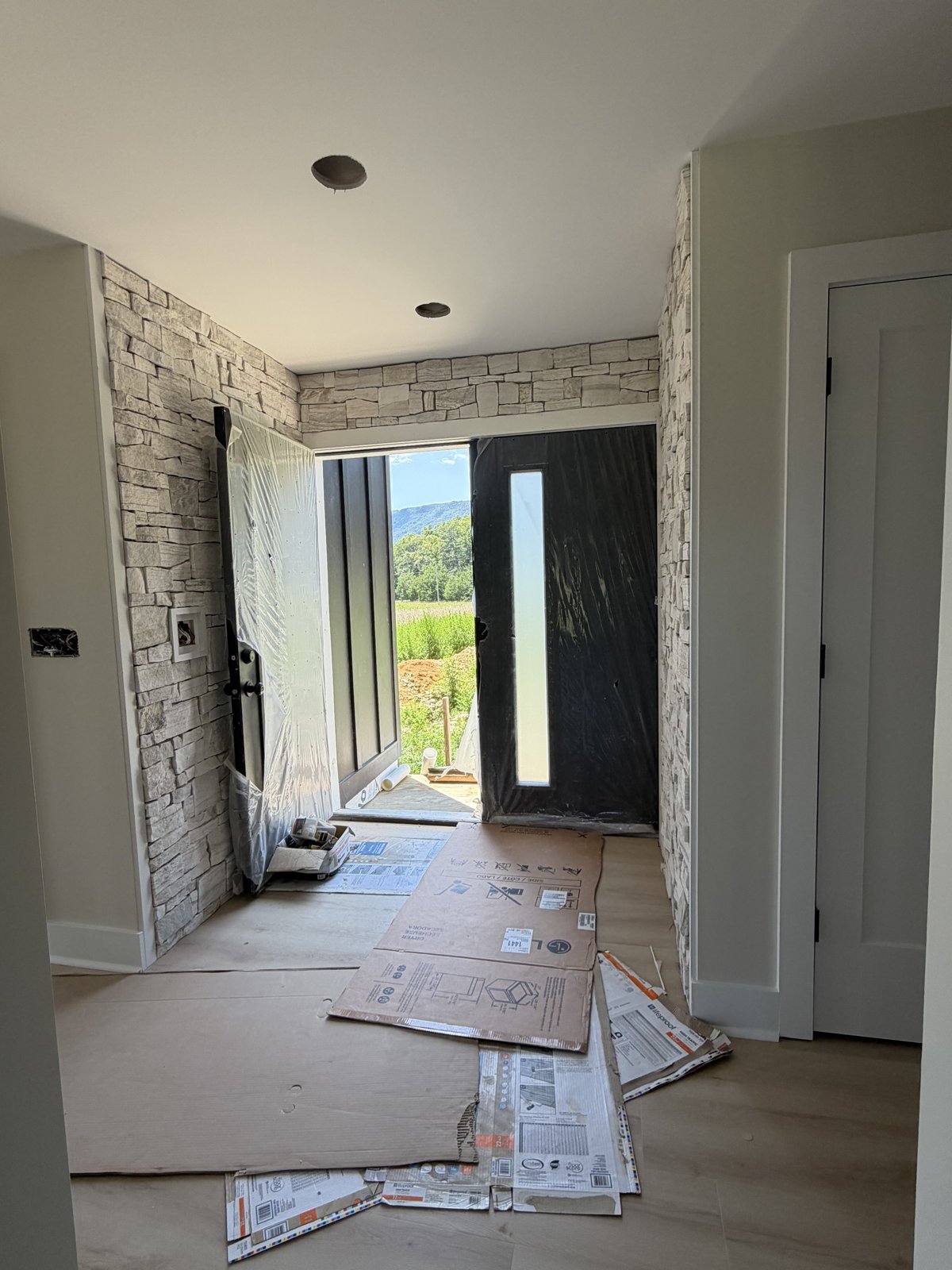 View through the stone foyer and black entry door to the mountains