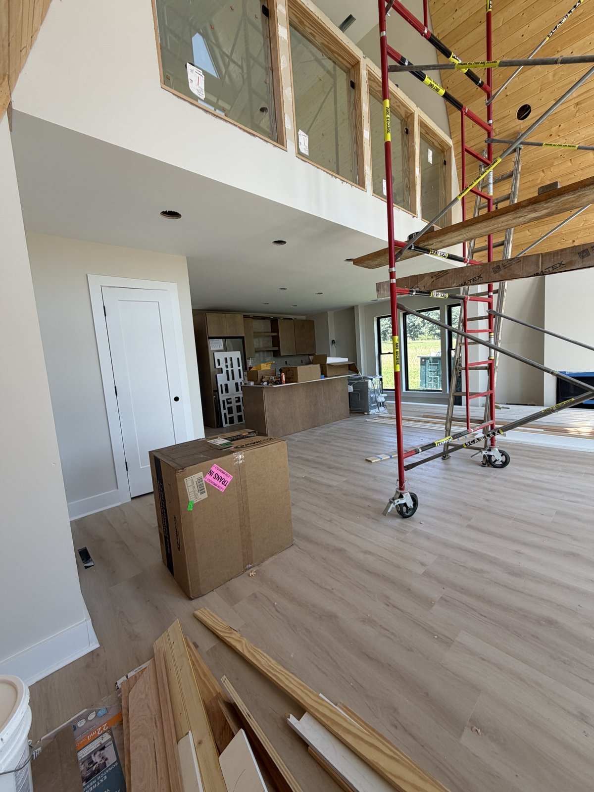 Great room looking toward the kitchen, wood wall and plank floors in
